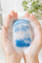 Hands holding a lathered hand-felted alpaca soap bar with rich suds