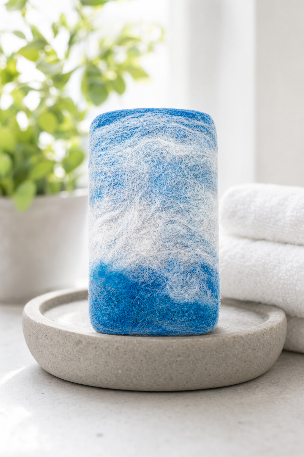 Hand-felted alpaca soap in Ocean Breeze, displayed on a natural stone dish in a bright spa bathroom